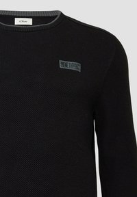 Schwarzer Strickpullover mit einem strukturierten Muster, ausgestattet mit einem grauen Rippenkragen und einem kleinen Logopatch auf der Vorderseite. Klassisches Rundhals-Design.