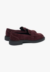 Bordeaux suede instappers met een platte zwarte rubberen zool, franjes en contrasterende stiksels rond de bovenkant.