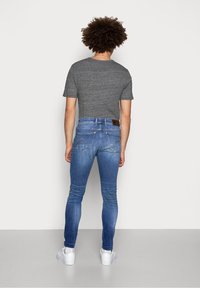 Grå bomulls t-shirt, blå slim-fit jeans med bakfickor och vita sneakers. Enkel design med en mjuk textur och avslappnad passform.