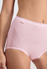 Jasnoróżowa bawełniana bielizna damska o wysokim stanie, z gładką powierzchnią i delikatnym koronkowym wykończeniem wzdłuż pasa. Widoczna mała metka marki.