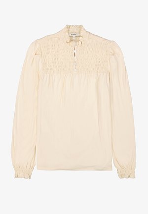 Blusa de manga larga color crema con detalle de pecho fruncido, cuello con volantes y cierre de botones, que presenta puños elásticos para un efecto recogido.