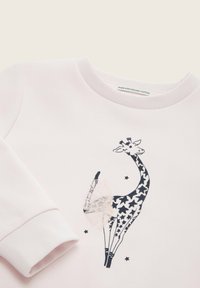 Lichtroze sweatshirt van biologisch katoen met een zwart-wit giraffe-ontwerp, sterpatronen en een tule accent op de staart.