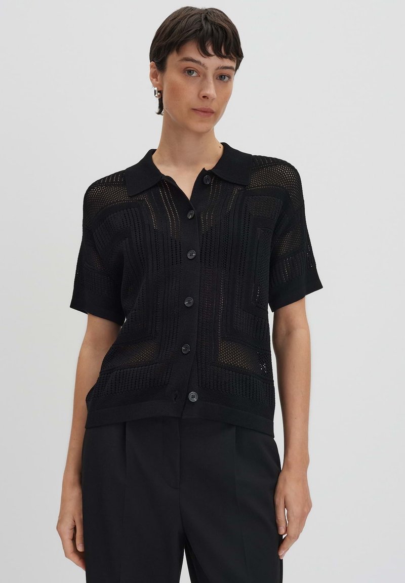 Schwarzes Strickshirt mit kurzen Ärmeln und Knopfleiste, mit einem strukturierten Muster und einem umlegbaren Kragen.