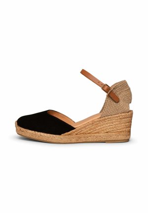 Alpargata cuña negra de punta cerrada con plataforma de yute trenzado y correa de tobillo marrón con hebilla sobre fondo blanco.