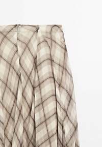 Brauner und cremefarbener karierter Rock mit Falten, ausgestattet mit einer glatten Textur und einem Reißverschluss auf der Rückseite. Hergestellt aus leichtem Stoff.