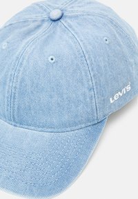 Világoskék farmer sapka, ívelt karimával, fehér varrással és kiemelkedő fehér "Levi's" logóval az oldalán. Textúrált anyag.
