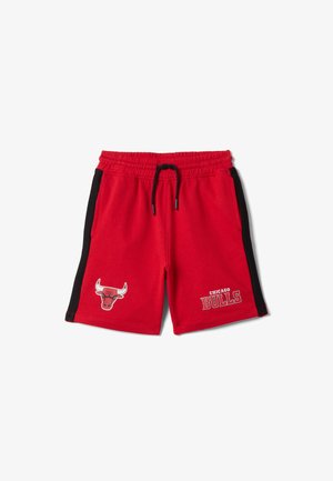 Shorts de sport rouges avec des bandes latérales noires, logo des Chicago Bulls sur la jambe gauche et taille à cordon sur fond blanc.