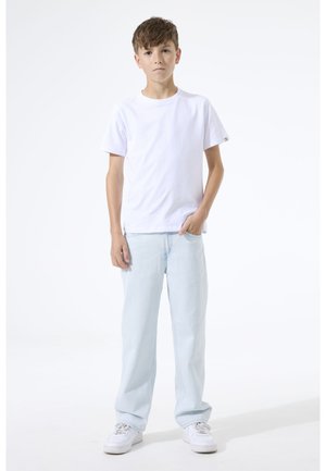 T-shirt en coton blanc, coupe décontractée, associé à un jean en denim bleu clair. Des baskets blanches complètent la tenue. Design simple et décontracté.