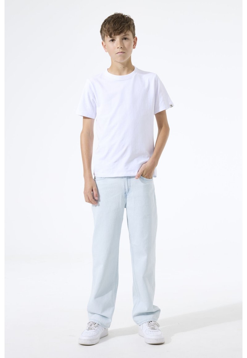 Weißes Baumwoll-T-Shirt, lockere Passform, kombiniert mit hellblauen Jeans. Weiße Sneaker vervollständigen das Outfit. Einfaches, lässiges Design.