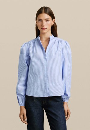 Blusa de botones azul claro con rayas verticales, mangas abullonadas y cuello mandarín. La tela parece suave con un ligero brillo.