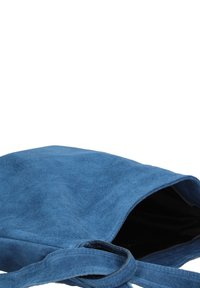 Sac fourre-tout en suède bleu avec une texture douce, doté d'une poignée unique et d'un haut ouvert, révélant une doublure intérieure noire.