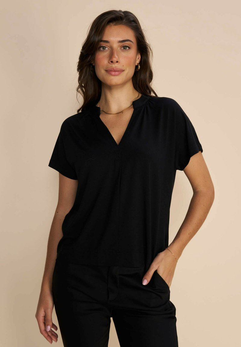 Black short-sleeve top with a V-neck and relaxed fit, made from soft fabric. Features subtle draping and a straight hem.