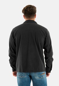 Zwarte corduroy overhemd met een kraag en lange mouwen, met een verticale ribbelstructuur. Draag het over een paar blauwe jeans voor een casual uitstraling.