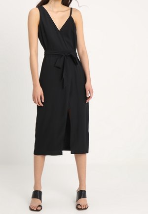 Abito midi senza maniche di colore nero con scollatura a V, vita accentuata da una cintura e spacco frontale. Realizzato in un tessuto liscio con una texture morbida.