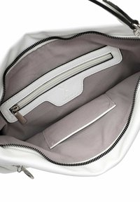 Interno della borsa bianca con una morbida fodera in tessuto grigio, dotato di una tasca con cerniera e una tasca a scomparsa, tutte con finiture in contrasto nere.