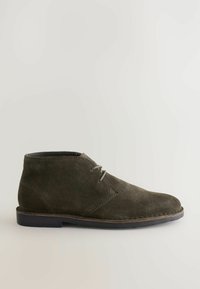 Botas de tobillo de ante verde olivo con punta redondeada, cordones simples y suela negra contrastante. Presenta acentos de costura minimalistas.