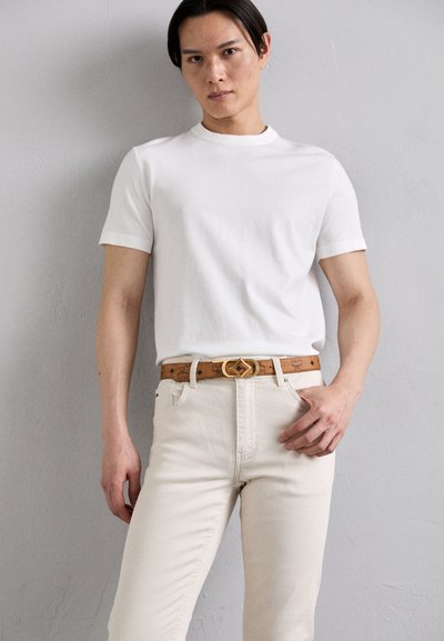 White short-sleeve t-shirt, beige high-waisted jeans, and a light brown belt with a gold buckle feature. Simple, clean design with no patterns.