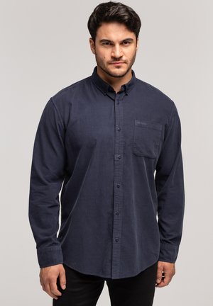 Granatowa koszula z długim rękawem na guziki, z kołnierzykiem, pojedynczą kieszenią na piersi oraz teksturowanym materiałem. Frontowe guziki i mankiety dopełniają projekt.