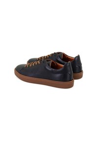 Baskets en cuir noir avec surface texturée, lacets marron et semelle en caoutchouc. Bout rond et design minimaliste avec un profil bas.