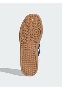 Az Adidas sneaker talpa bézs színű gumiból készült, mintás tapadással. A márka logója a sarok közelében van benyomva.