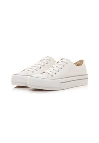 Zapatillas de lona blancas con perfil bajo, punta redonda y ojales plateados; cuentan con una suela de goma gris claro con detalles texturizados.