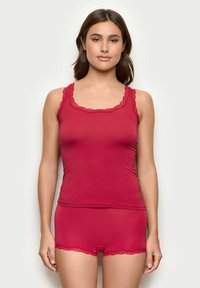 Rød tank top med blondekant og matchende shorts i blødt, elastisk materiale. Stoffet er glat med en tætsiddende pasform og fine blonder.