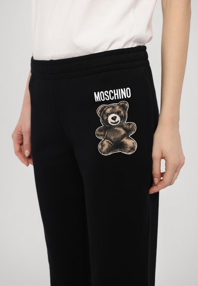 Zwarte sweatpants met ribbelde tailleband, met een beer grafiek en het "MOSCHINO" logo in het wit op de linker bovenbeen. Zachte stoftextuur.