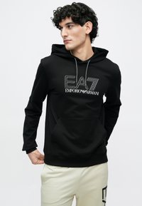 Čierna mikina s kapucňou a predným klokankovým vreckom, bielym logom EA7 Emporio Armani. Mäkký materiál s dlhými rukávmi a sťahovacími šnúrkami.