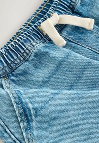 Şorturi din denim albastru deschis, cu un pantalon elastic și un șnur alb, având detalii vizibile de coasere.