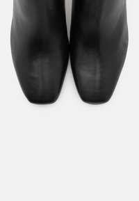 Svarta läderankelboots med spetsig tå. Mjuk textur och minimalistisk design. Inga synliga beslag eller mönster.