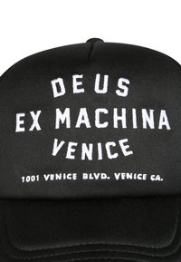 Gorra de béisbol negra con texto bordado en blanco: "DEUS EX MACHINA VENICE" y "1001 VENICE BLVD. VENICE CA." Textura de tela suave.