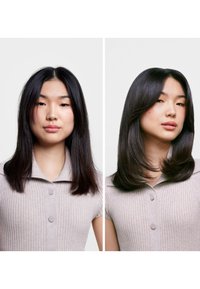 Due immagini affiancate mostrano una persona con capelli neri e lisci. A sinistra i capelli sono di media lunghezza, mentre a destra sono lunghi e lisci. Entrambe le immagini presentano una polo grigia chiara a coste con bottoni.