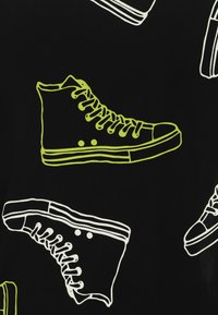 Schwarzer Stoff mit umreißenden Illustrationen von High-Top-Sneakern. Merkmale sind weiße und neongrüne Farben, Details an Schnürsenkeln und Sohlen.