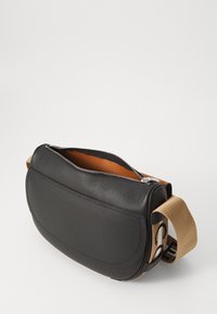 Sort læder-sling taske med en tekstureret overflade, lynlåslukning og en kontrasterende orange inderside. Har en beige rem med trykte accenter.