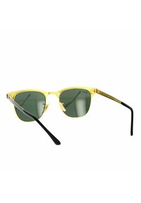 Occhiali da sole con montatura in metallo giallo e lenti verdi, dotati di aste nere e una forma slanciata con un design moderno.