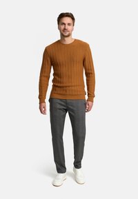Brown ribbed sweater with long sleeves, gray checkered trousers, and white sneakers. The outfit presents a casual yet structured look.