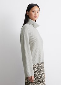 Lys grå ribbestrikket genser med høy krage og lange ermer, kombinert med et mønstret skjørt med svart og beige dyreprint.