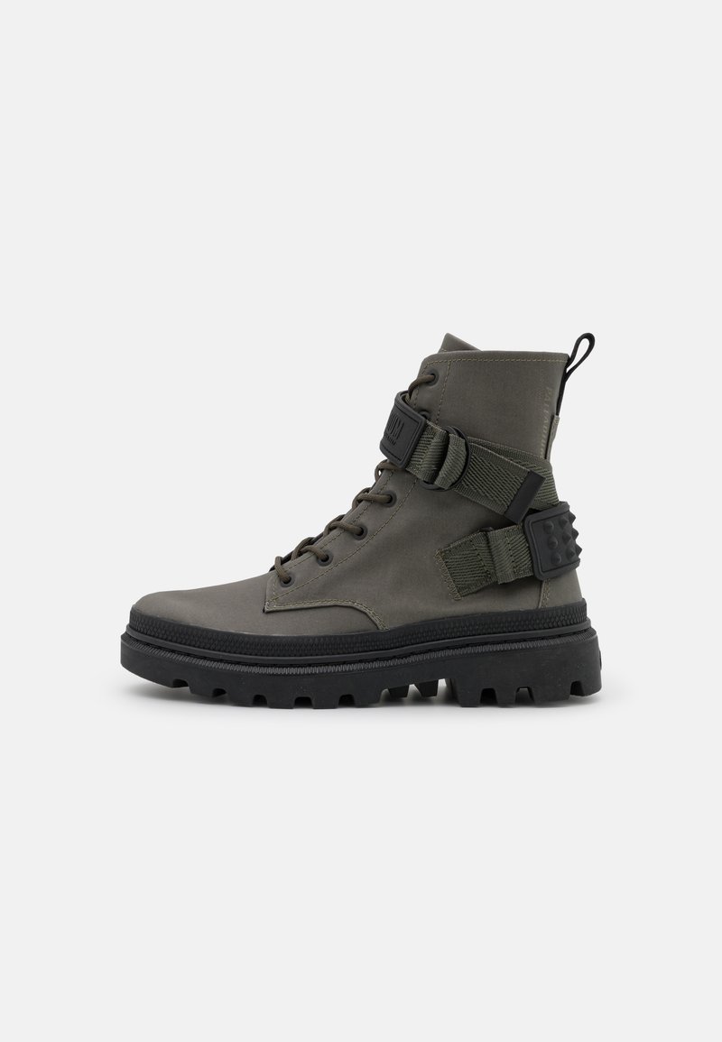 Botas de tobillo para hombres en verde oscuro, fabricadas con material sintético, cuentan con una suela de goma, correa ajustable y acentos de herrajes metálicos.