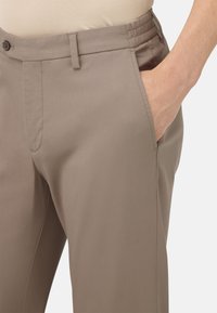 Pantalones beige con una textura suave, corte recto y bolsillos laterales. Presenta un cierre de botón y una cinturilla elástica para mayor comodidad.