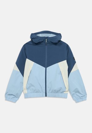 Αντιανεμικό μπουφάν με μπλοκ χρωμάτων σε αποχρώσεις μπλε και ανοιχτού μπλε. Διαθέτει κουκούλα, μπροστινό φερμουάρ και ελαστικές μανσέτες και τελείωμα.