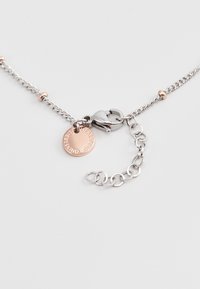 Zilveren ketting met een roségouden hanger. Bevat een kreeftsluiting en een klein label met tekst. Inclusief verstelbare lengte schakels.