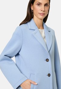 Lichtblauwe blazer met een gestructureerde kraag, twee knopen en een zachte stof. Beschikt over zijzakken en een nette, op maat gemaakte uitstraling.