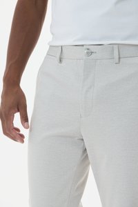 Pantalons gris clair en tissu texturé, dotés d'une fermeture à bouton, de passants de ceinture et d'un design à coupe classique avec des poches latérales.