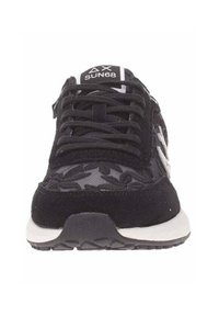 Zapatillas deportivas negras con parte superior de ante y malla, detalle de patrón de hojas, frontales con cordones texturizados y suela de goma blanca. Presenta el logotipo en la lengüeta.