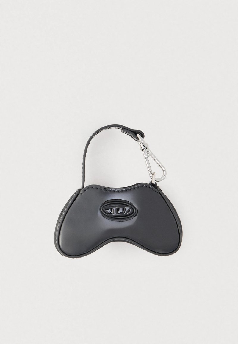 Čierne kožené púzdro v tvare herného ovládača s náramkom na zápästie a strieborným kovovým zapínaním na jednoduchom svetlom pozadí.