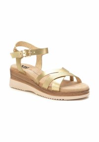 Sandalias de cuña de imitación cuero dorado con tiras entrelazadas, plantilla de corcho y un acento texturizado. Correa ajustable en el tobillo con detalle de hebilla.