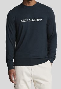 Maglione blu navy con collo a giro e maniche lunghe, con logo bianco "LYLE & SCOTT" sul petto. Polsini e orlo a costine.