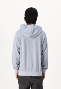 Lyseblå hoodie lavet af blødt stof med en kengurulomme, snoretræk i hætten og ribbede mansjetter på lange ærmer.