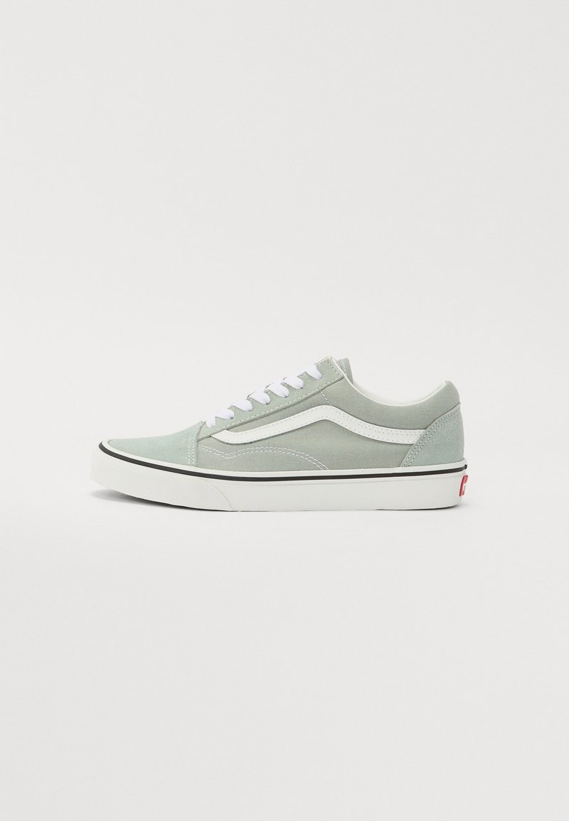 Baskets en daim vert clair avec des accents blancs, des panneaux texturés et des lacets plats blancs. Elles présentent une semelle extérieure noire et un logo rouge sur le talon.