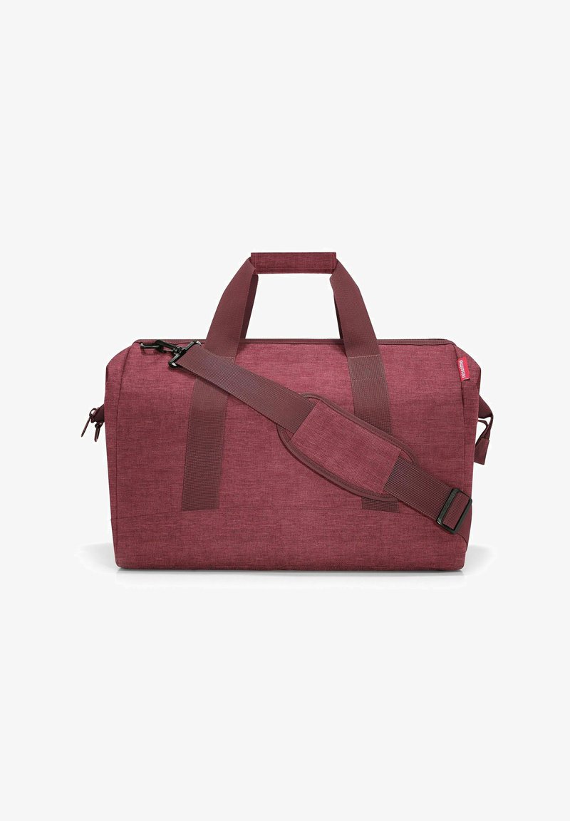 Sac de voyage bordeaux en tissu texturé, doté de deux poignées et d'une bandoulière réglable. Une fermeture éclair orne le dessus.